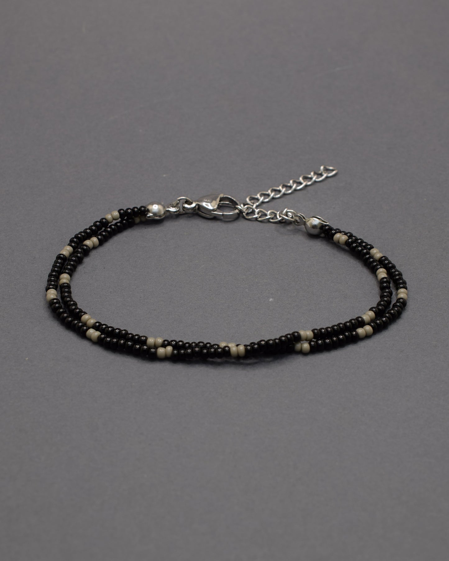 Pulseira dupla de missangas pretas com padrão cinzento. Combina força e equilíbrio, revelando um brilho subtil de elegância moderna.