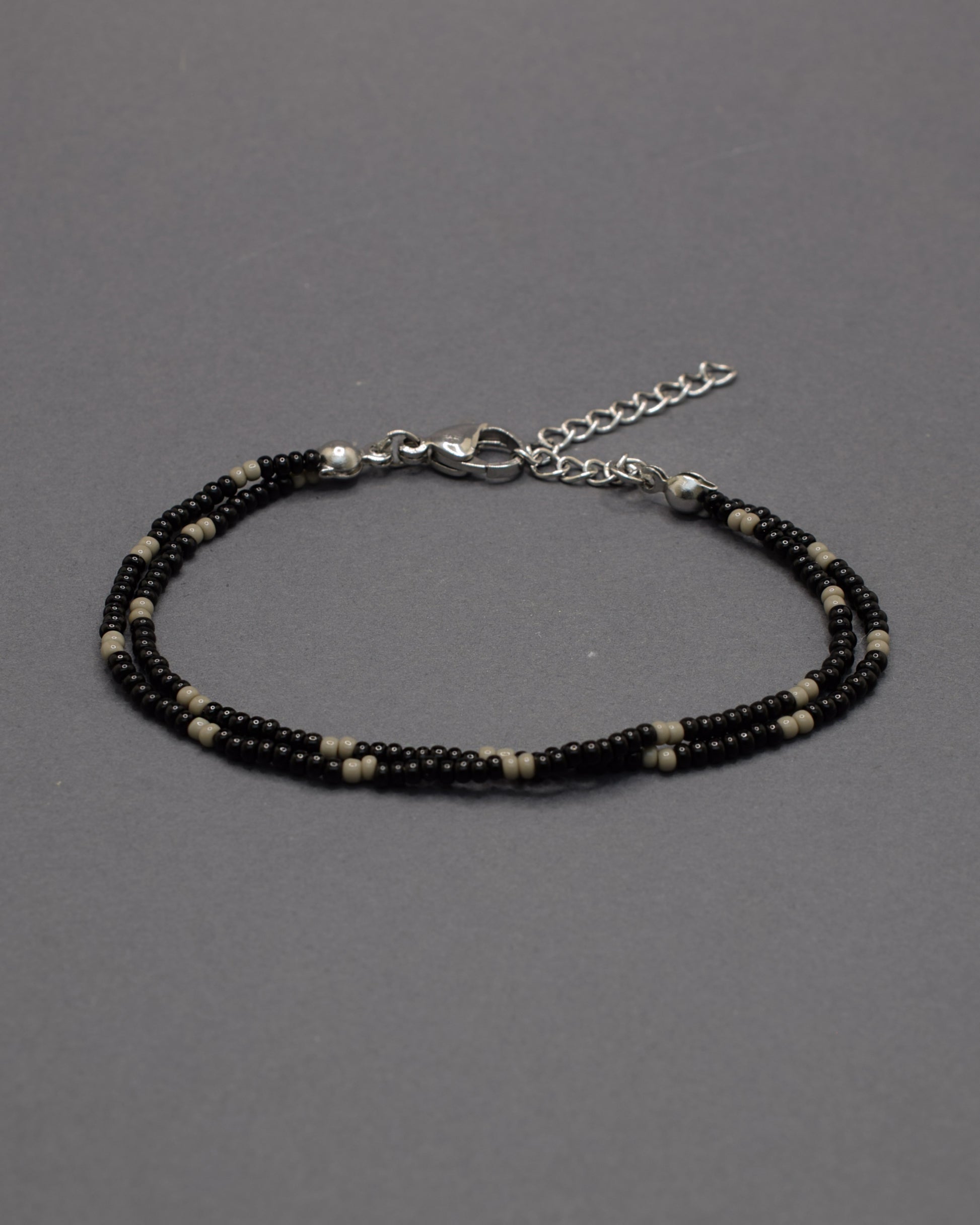 Pulseira dupla de missangas pretas com padrão cinzento. Combina força e equilíbrio, revelando um brilho subtil de elegância moderna.