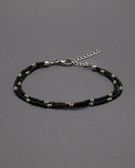 Pulseira dupla de missangas pretas com padrão cinzento. Combina força e equilíbrio, revelando um brilho subtil de elegância moderna.