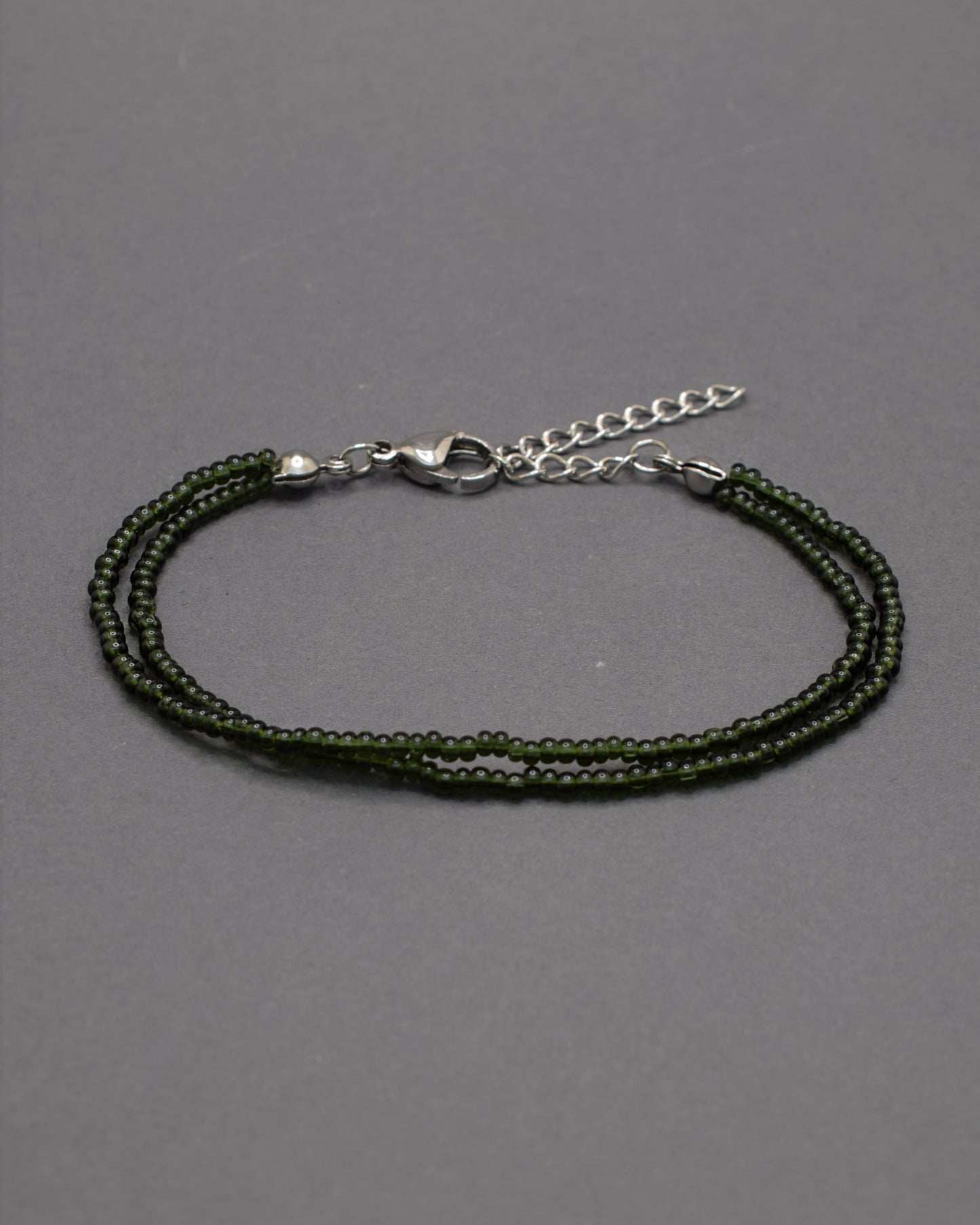 Pulseira dupla de missangas verde escuras semitransparentes. Design artesanal e elegante, ideal para um look sofisticado.