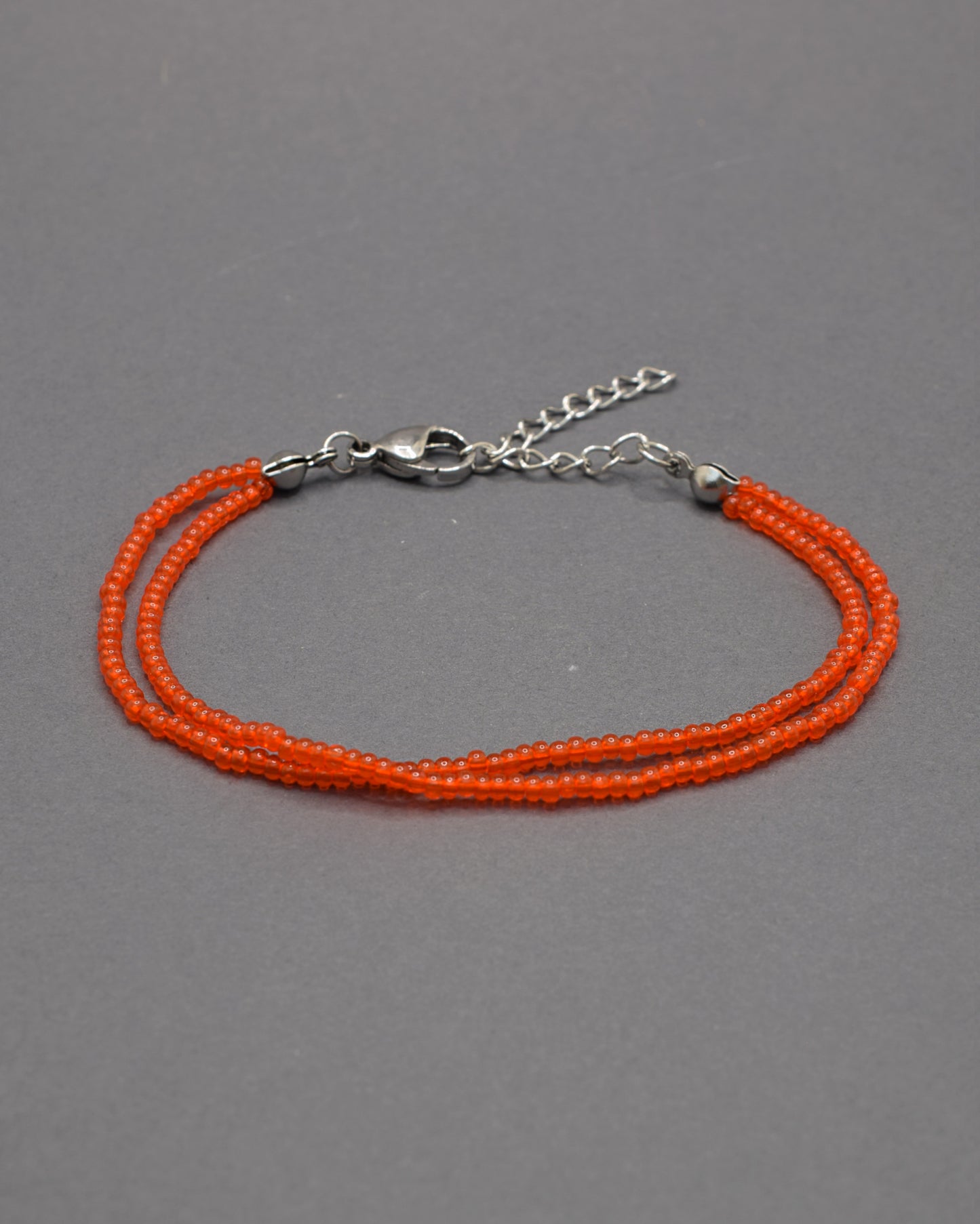 Pulseira dupla de missangas vermelhas-alaranjadas semitransparentes. Design artesanal e vibrante, perfeita para adicionar um toque de cor e elegância ao seu look.