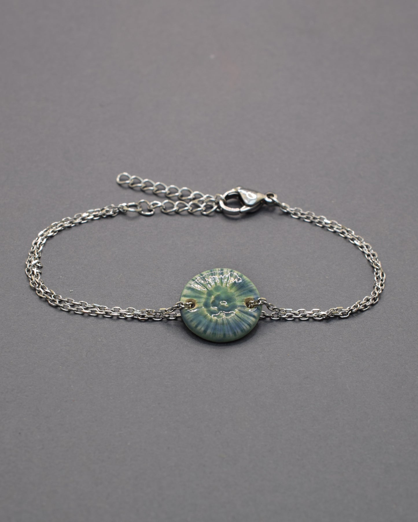 Pulseira delicada com pendente flor do mar em cerâmica verde musgo, inspirada na natureza e perfeita para um toque orgânico e sofisticado ao seu look.