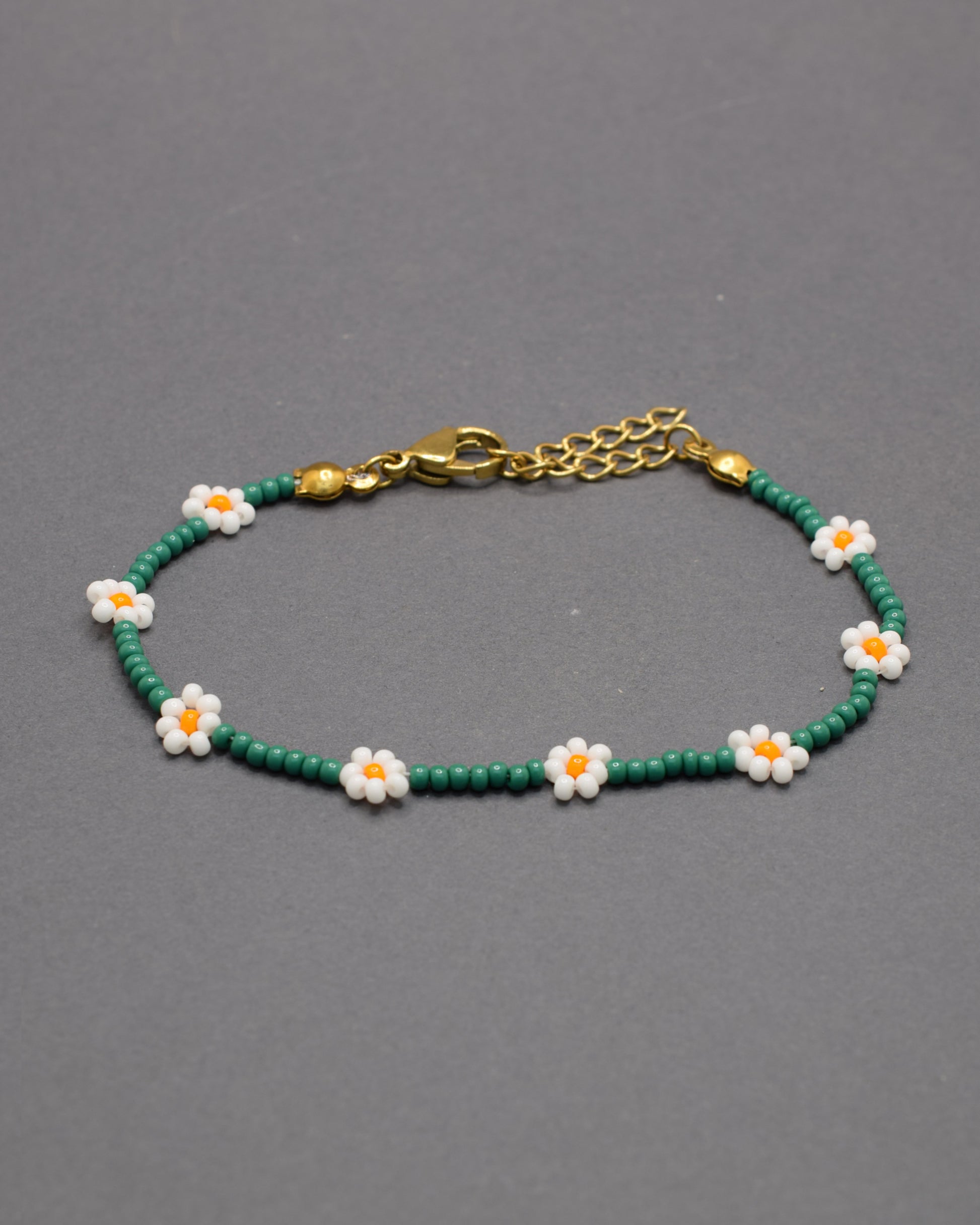 Pulseira de flores brancas com missangas verdes, elegante e natural, ideal para um look fresco e sofisticado com inspiração na natureza.