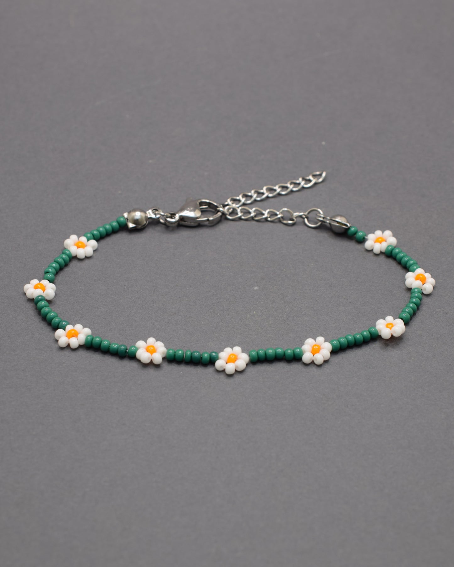 Pulseira de flores brancas com missangas verdes, elegante e natural, ideal para um look fresco e sofisticado com inspiração na natureza.