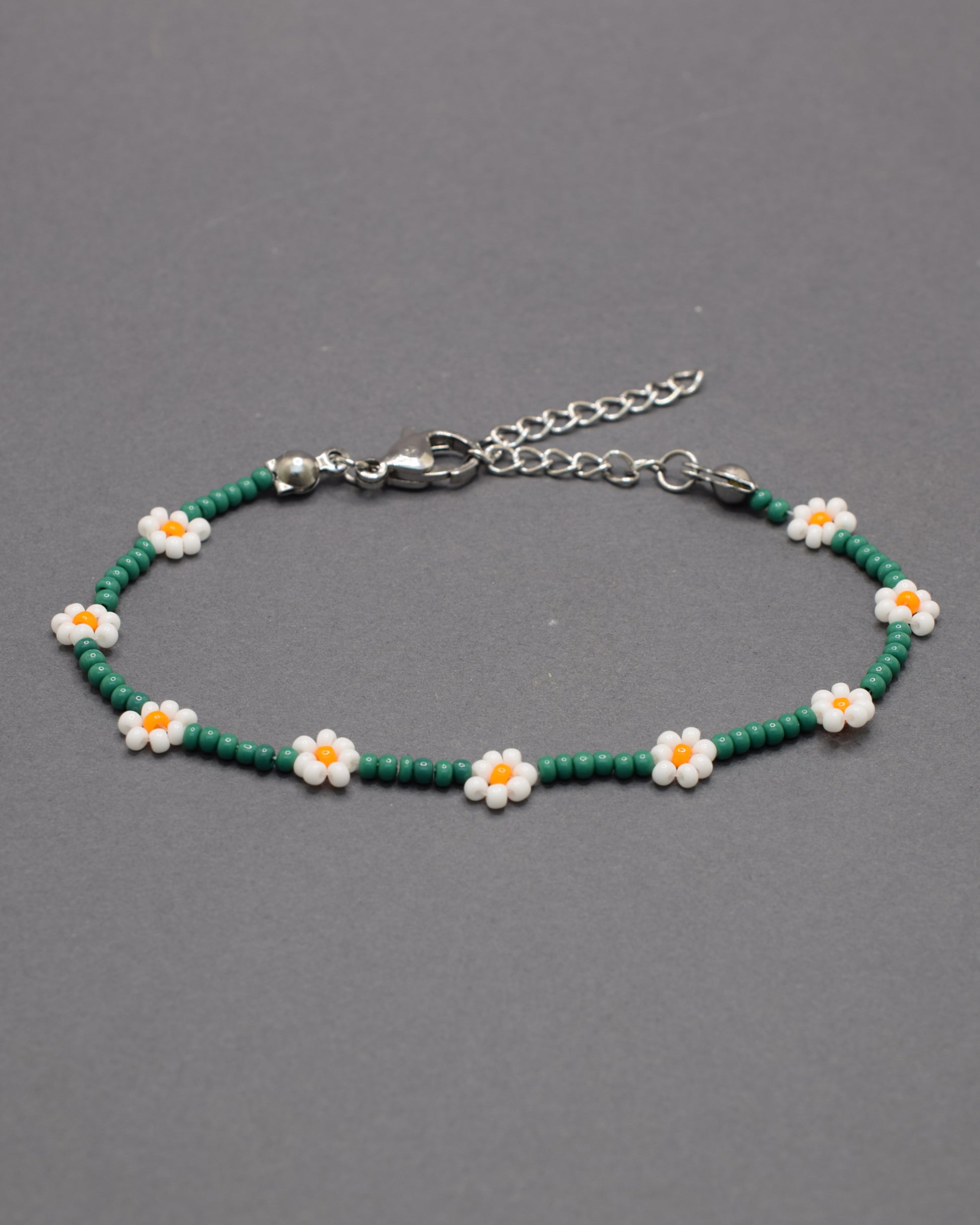 Pulseira de flores brancas com missangas verdes, elegante e natural, ideal para um look fresco e sofisticado com inspiração na natureza.