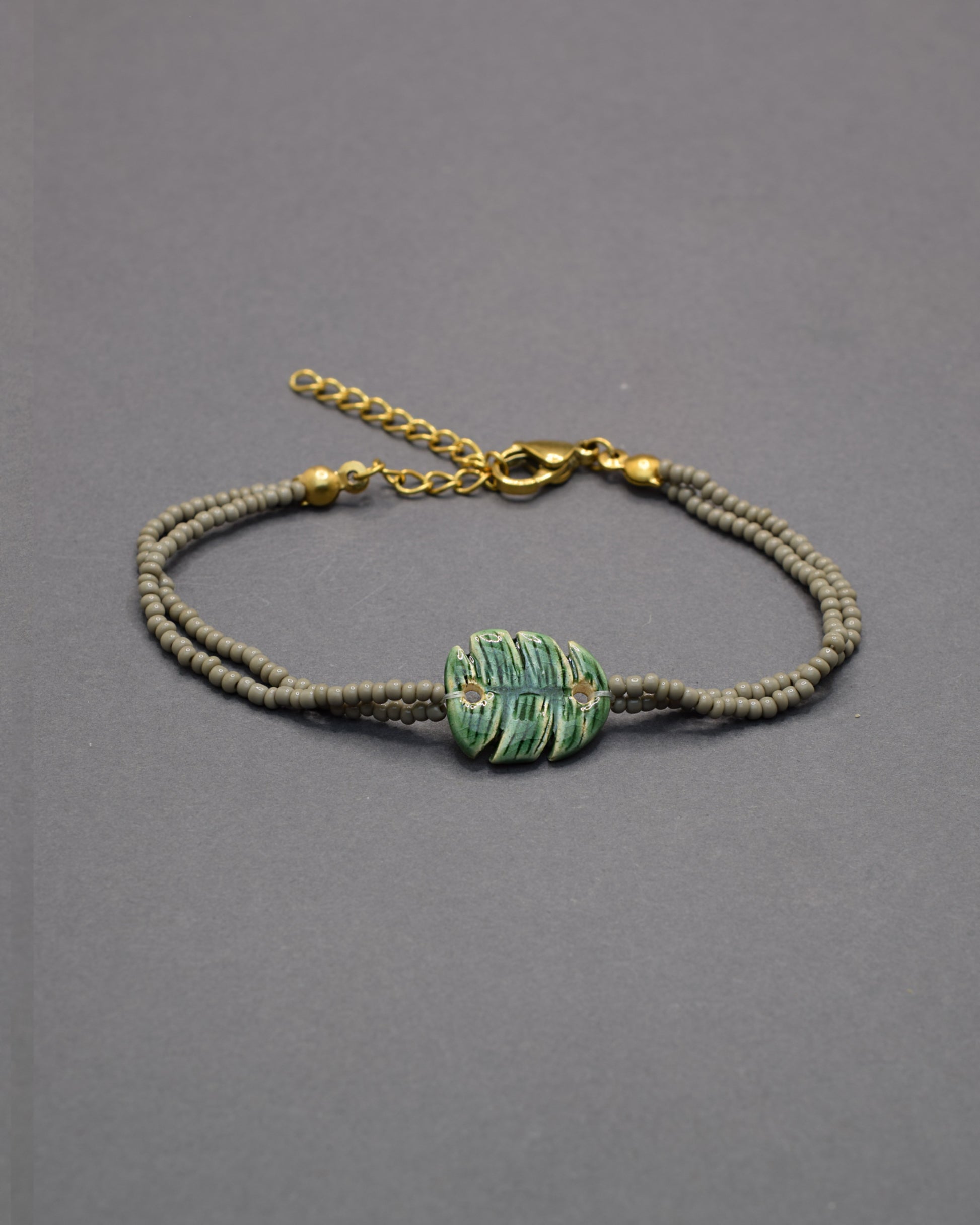 Pulseira delicada com pendente de folha verde em cerâmica, inspirada na natureza, leve e elegante para um toque fresco e sofisticado no seu dia a dia.