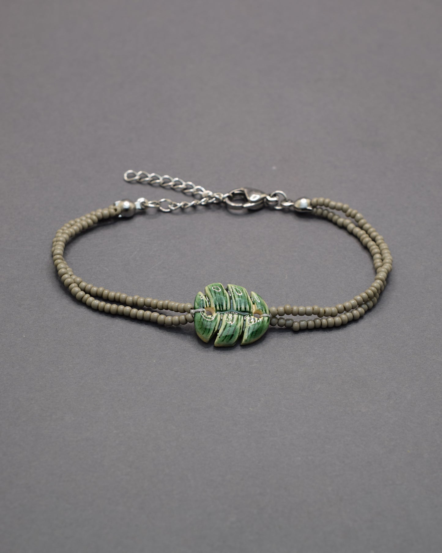 Pulseira delicada com pendente de folha verde em cerâmica, inspirada na natureza, leve e elegante para um toque fresco e sofisticado no seu dia a dia.