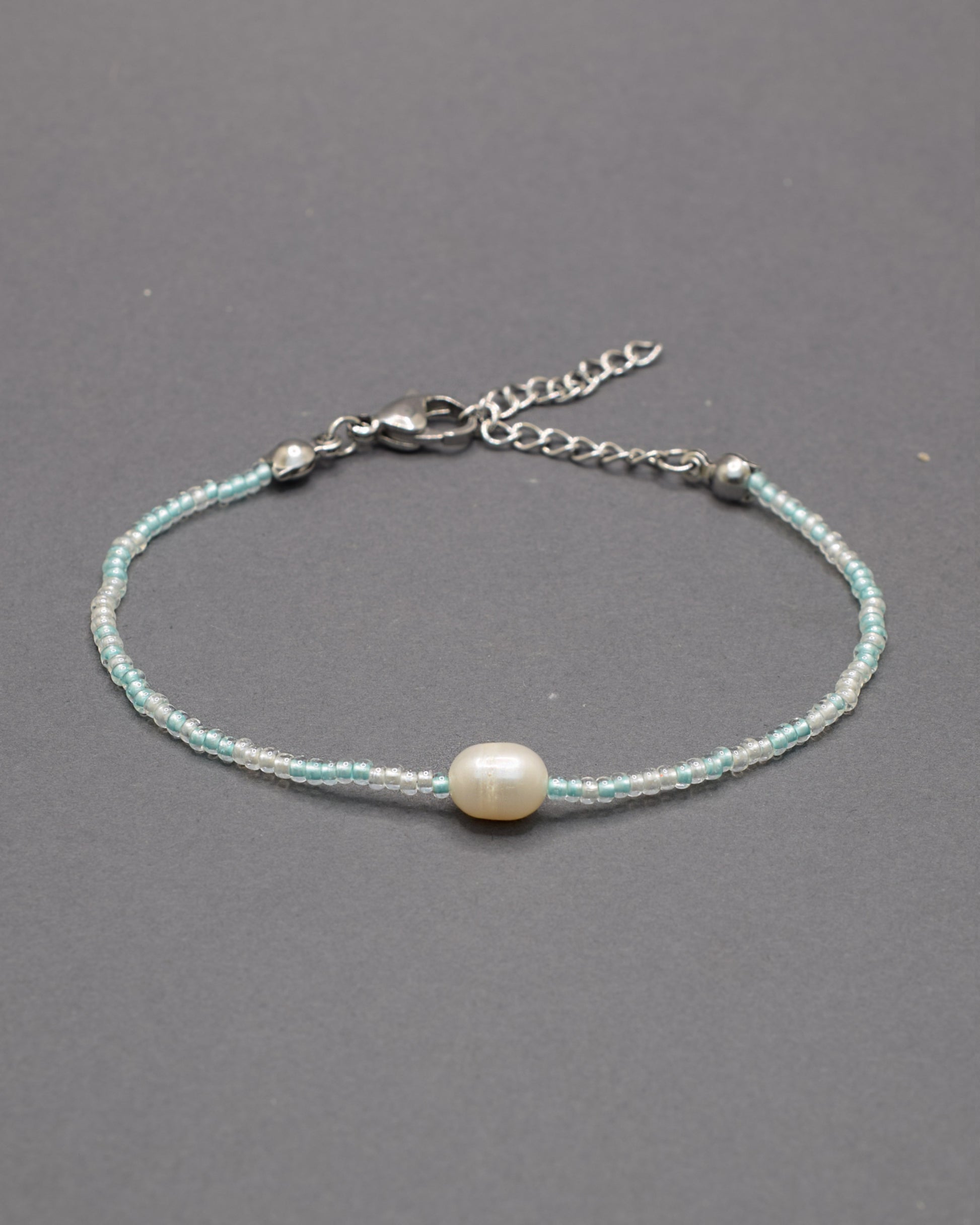 Delicada pulseira de missangas mix turquesa semitransparente com pérola, perfeita para um toque de elegância.