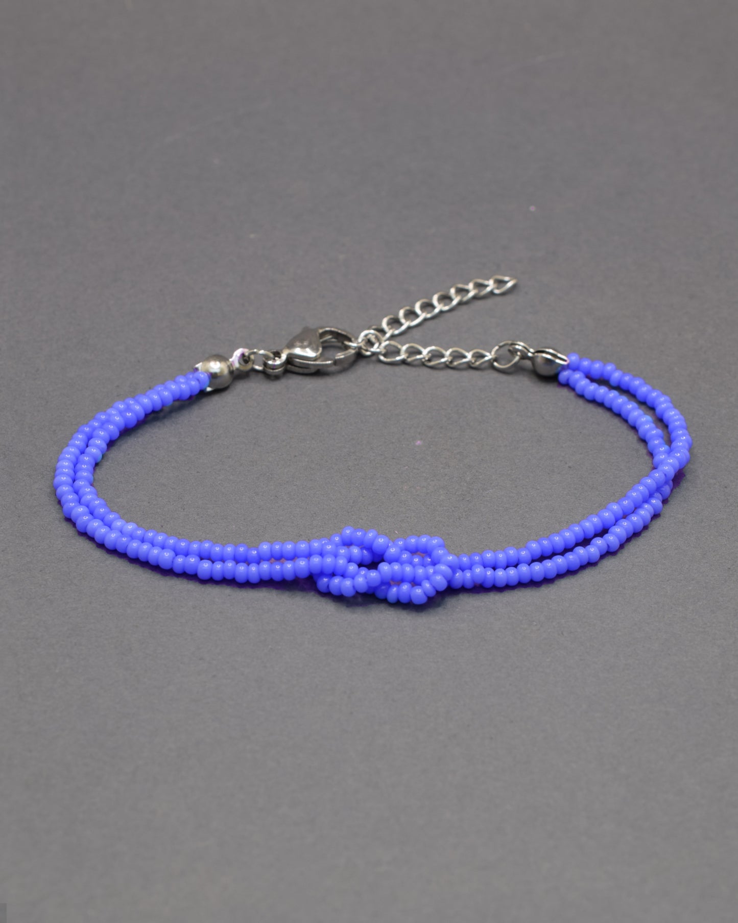 Pulseira dupla de missangas azul neon com nó, vibrante e leve, perfeita para dar um toque luminoso e moderno ao teu look.