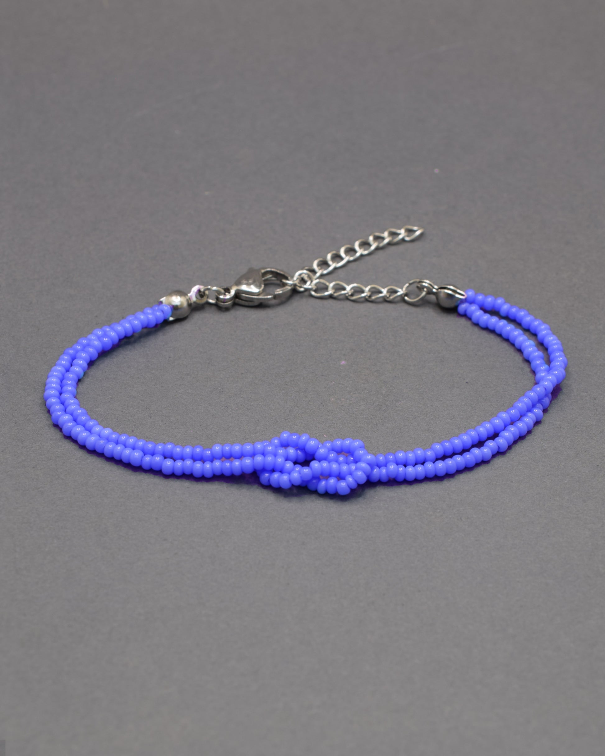 Pulseira dupla de missangas azul neon com nó, vibrante e leve, perfeita para dar um toque luminoso e moderno ao teu look.