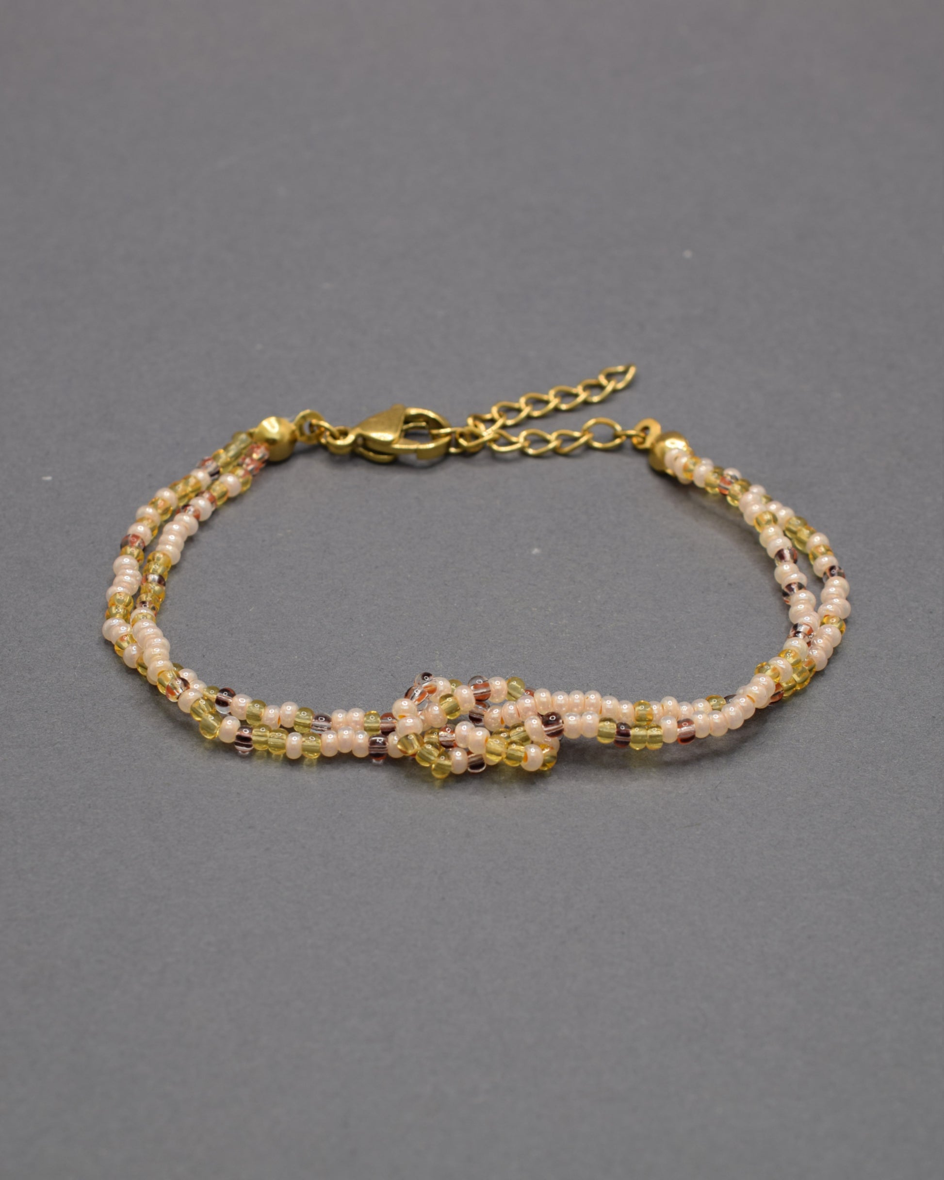 Pulseira dupla de missangas mix dourado com nó, elegante e luminosa, perfeita para acrescentar um toque subtil de brilho ao teu look diário.