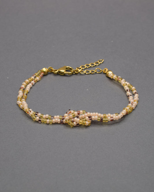 Pulseira dupla de missangas mix dourado com nó, elegante e luminosa, perfeita para acrescentar um toque subtil de brilho ao teu look diário.