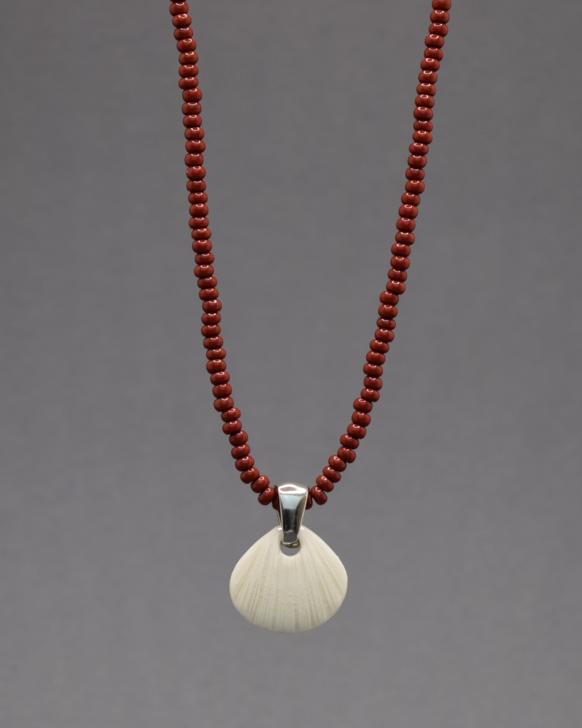 Colar com pendente de porcelana em forma de concha. Peça delicada, feita à mão, ideal para amantes do mar e do design artesanal.