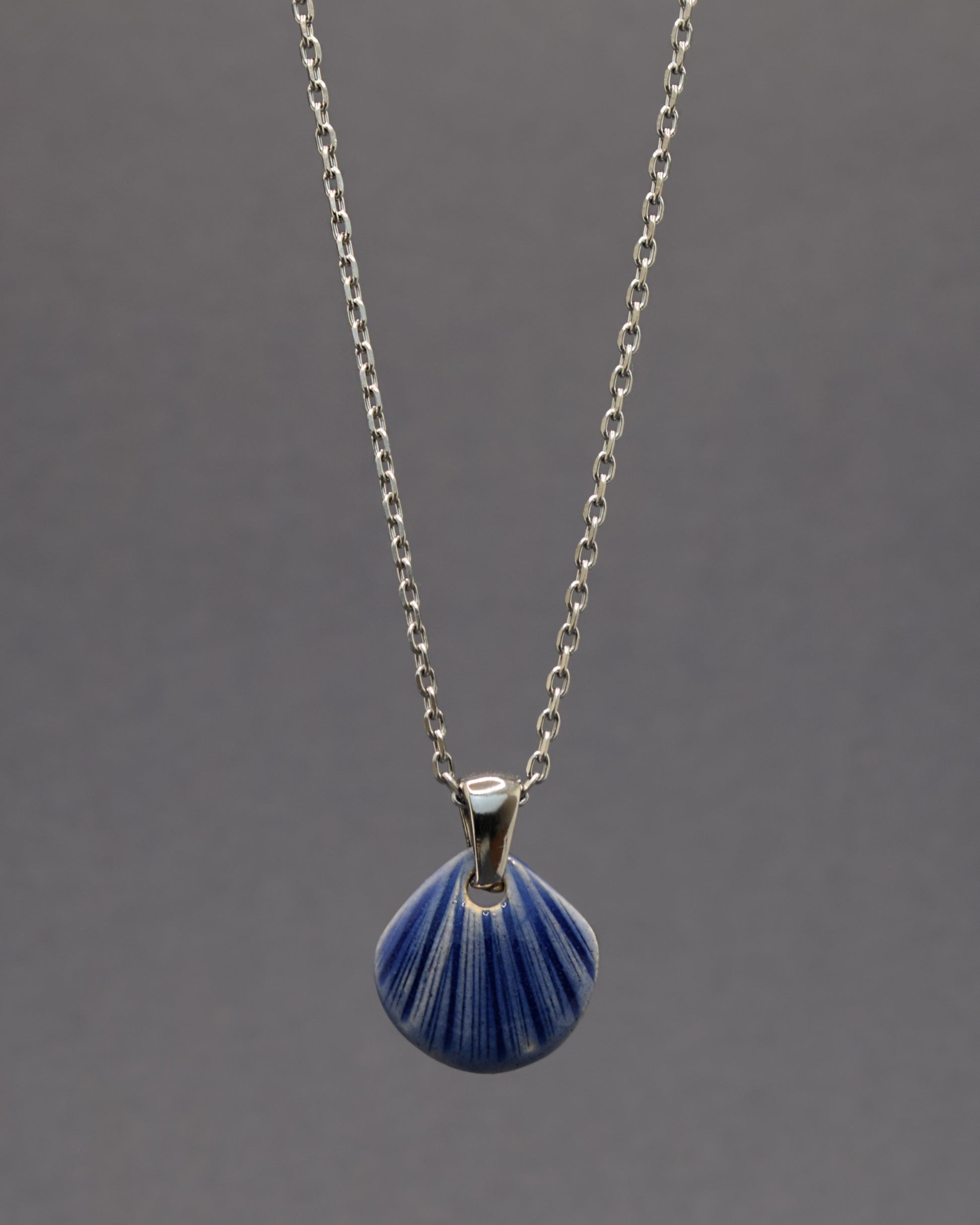 Colar artesanal com pendente de concha em cerâmica azul escuro, inspirado no mar e na serenidade. Elegante e versátil para qualquer ocasião.